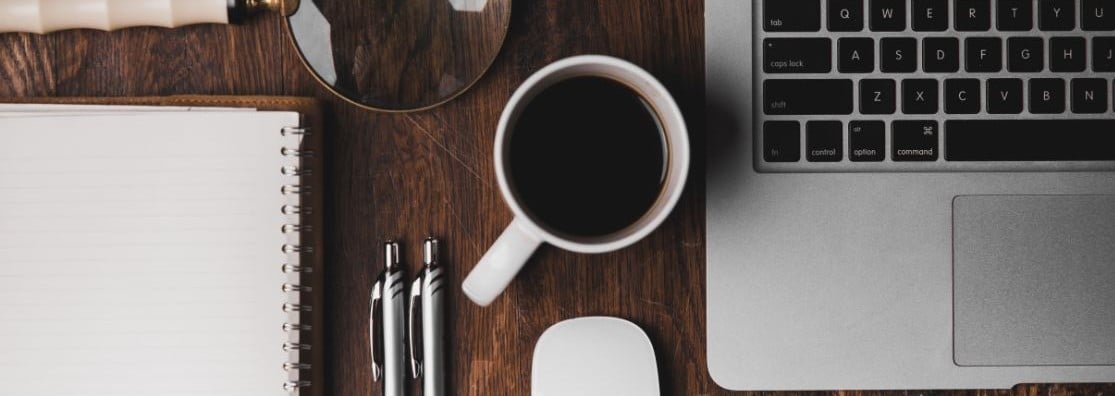 notebook keyboard coffee cup and pen on desk