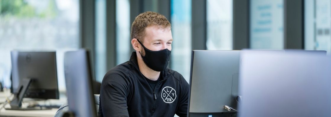 A student wearing a black face mask works at a computer in Maynooth University