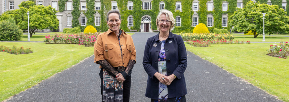 Image of smilling university president and Princess Zahra Aga Khan in front of historic university buildings
