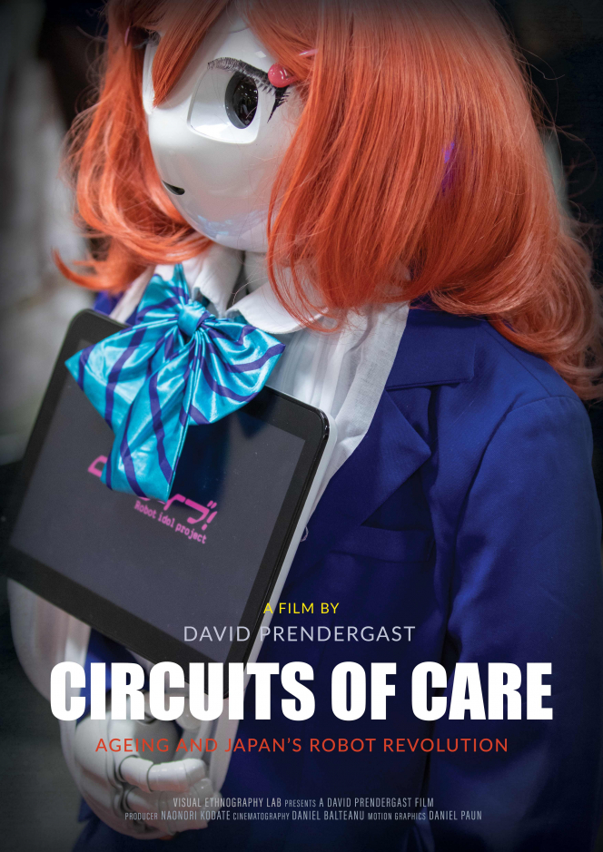 Text: Film by David Prendergast: Circuits of Care Ageing and Japan's Robot Revolution. Image in Background robot dressed in female clothing - blue suit white blouse and light blue cravat with a red wig holding an interactive tablet 