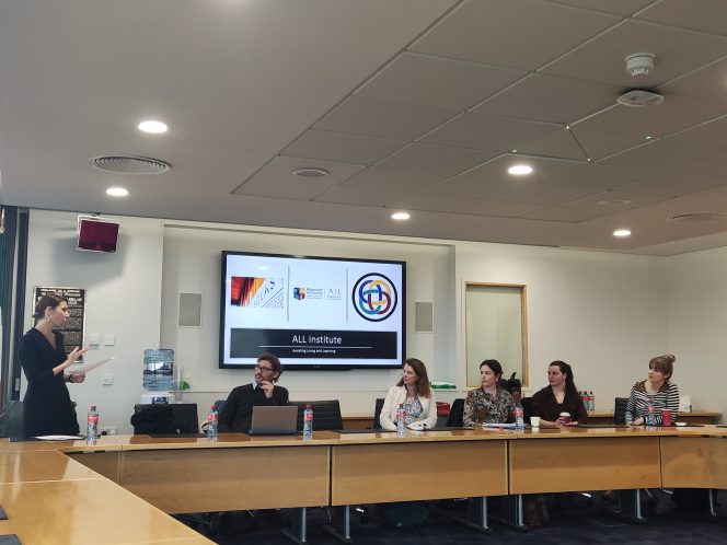 Panelists sitting at top table left to right Delia Ferri (standing), Vincenzo Tudisco, Nicola Mountford, Louise Veiling, Neasa Boyle, Holly Foley. Screen in the background with ALL Institute logo and Maynooth University logo on it.