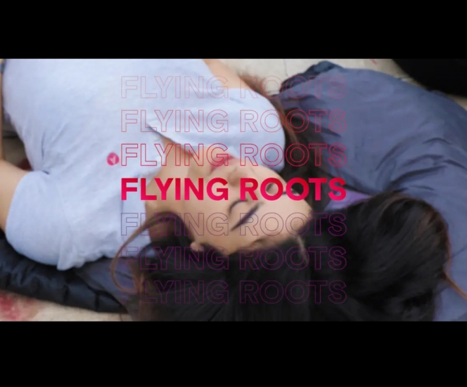 Still image taken from FLying Roots documentary. Shows one of the participants (Teenage girl) with eyes closed with Flying Roots in red in the foreground