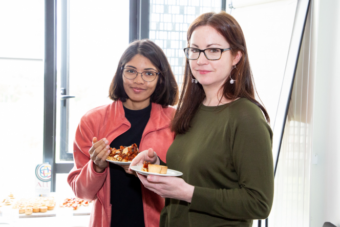 2 women smiling at the camera both holding plates of food