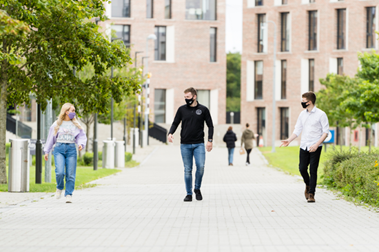 students wearing masks walk to campus from the new residence buildings