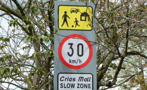 Road traffic signs showing children playing, speed limit of 30 km/h and saying Slow Zone