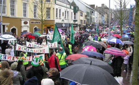 Street with Patrick's Day marchers and observers with umbrellas