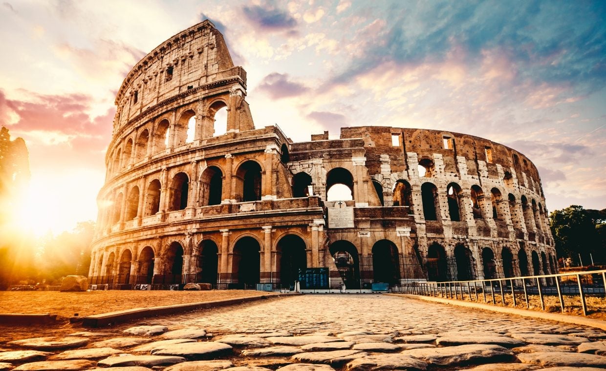 External shot of the Colosseum in Rome with sun setting to the left of picture