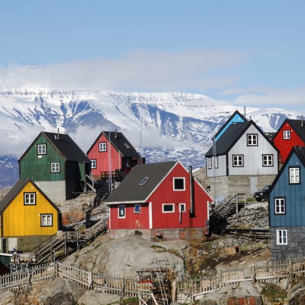 Different colour houses, with ice cliffs in the background - set in Greenland
