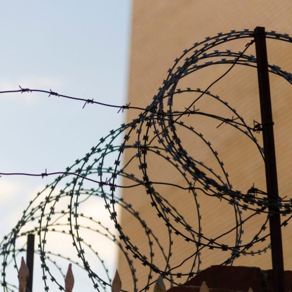 Roll of barbed wire on a wall between a brown wall and a blue sky