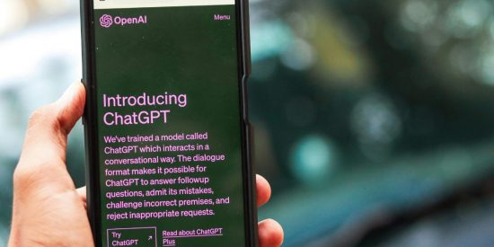 Hand holding a mobile phone with information about ChatGPT