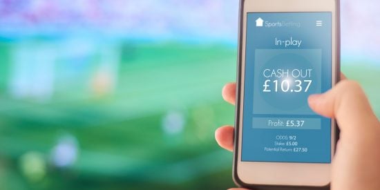 person holding phone with online betting app on screen