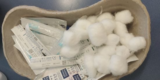 An image of a medical kidney bowl holding cotton swabs and other dressings