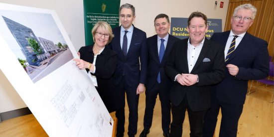 MU President Eeva Leinonen stands with three government ministers and DCU President and a placard showing student housing plans