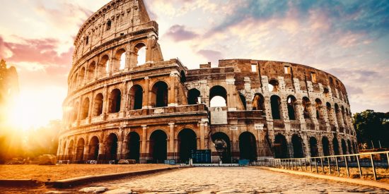 External shot of the Colosseum in Rome with sun setting to the left of picture