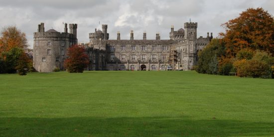 Grey castle with a round section on the left with grass in front of it
