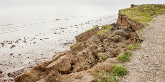 Coastal footpath with grassy verge crumbling into the sea