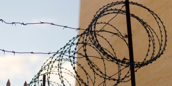 Roll of barbed wire on a wall between a brown wall and a blue sky