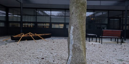 Ogham stone inscribed with 'Ollscoil Mhá Nuad' in ogham script (foreground) with traditional currach (background) in Garraí na Gaeilge in the Arts Building, Maynooth University