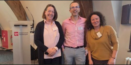 3 people stand beside a podium