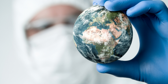 image of earth held between fingers in blue surgical gloves