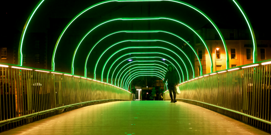 woman walking across a bridge with neon lighting 