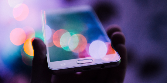 Mobile Smart Phone held in someone's hand with distorted colourful spheres over the top of the screen