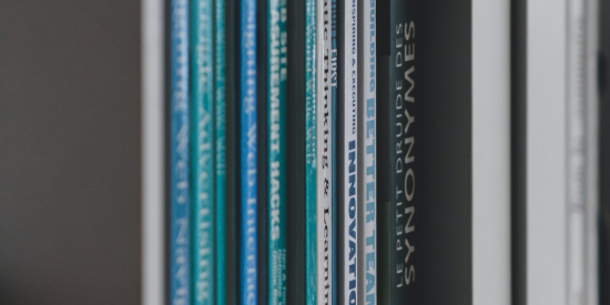 Magazines and books on a white shelf shot from an angle