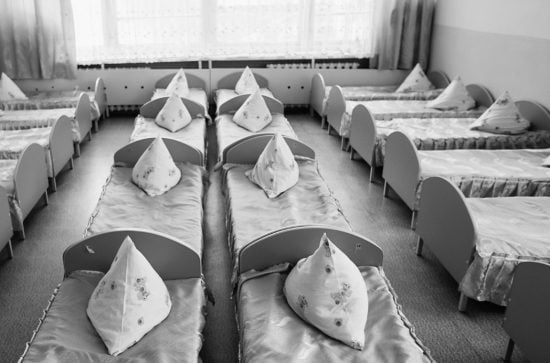 Rows of beds with grey covers and triangular pillows on top
