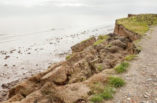 Coastal footpath with grassy verge crumbling into the sea